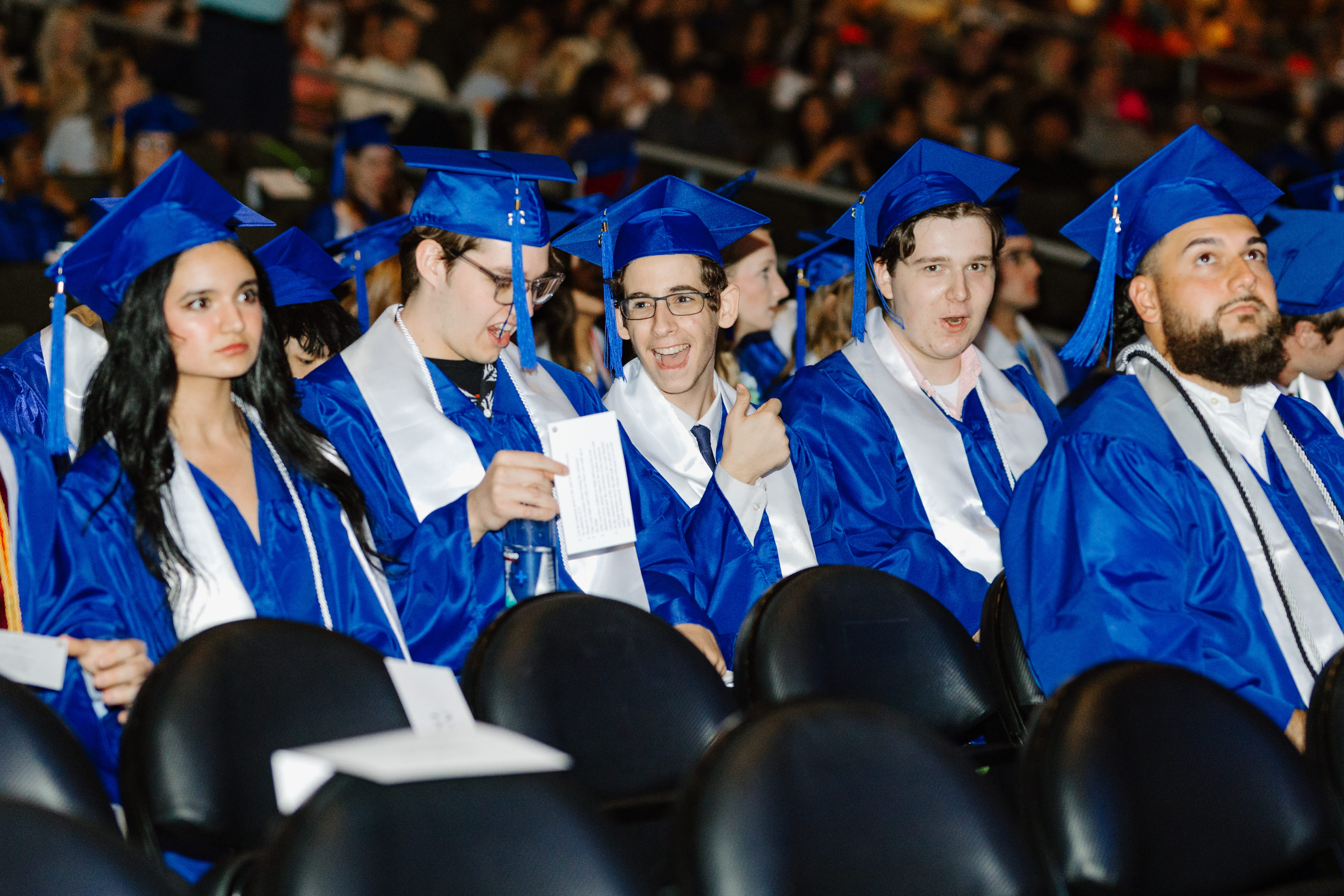 Students sitting at graduation in caps and gowns